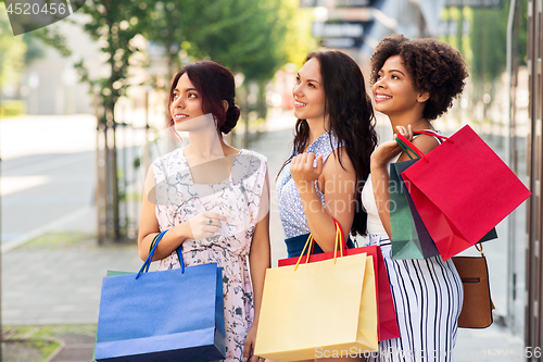 Image of happy women with shopping bags in city