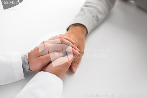 Image of close up of doctor holding senior patient hand