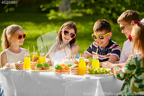 Image of happy kids with cake on birthday party in summer