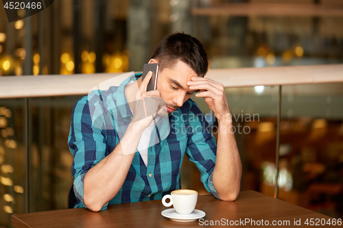 Image of man with coffee calling smartphone at restaurant