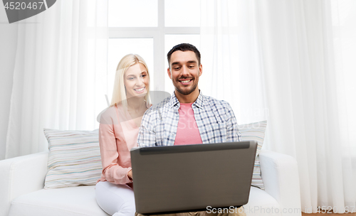 Image of smiling happy couple with laptop at home