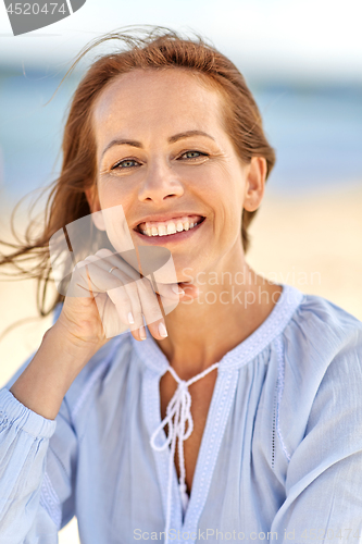 Image of portrait of happy smiling woman on summer beach