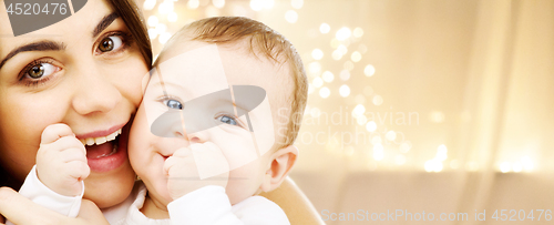 Image of close up of mother with baby over christmas lights