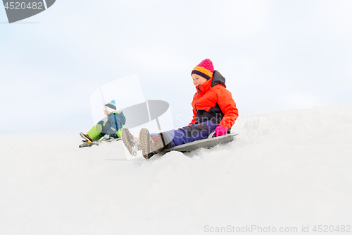 Image of happy kids sliding on sleds down hill in winter