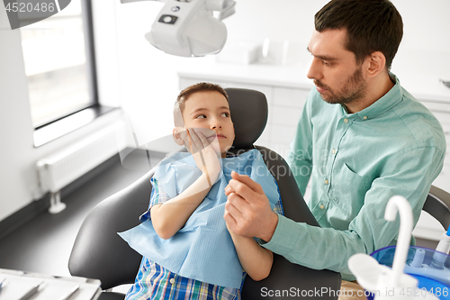 Image of father supporting son at dental clinic