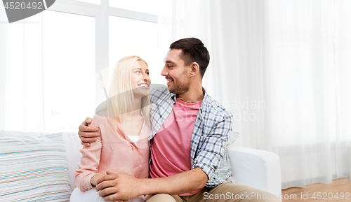 Image of smiling happy couple hugging on sofa at home