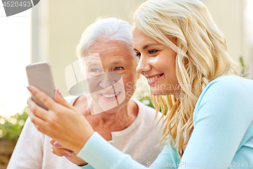 Image of daughter and senior mother with smartphone outdoor