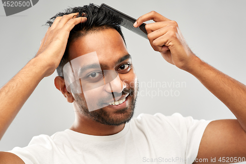 Image of happy indian man brushing hair with comb