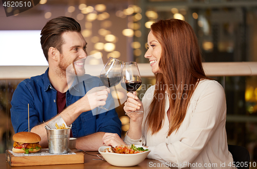 Image of couple eating and drinking red wine at restaurant