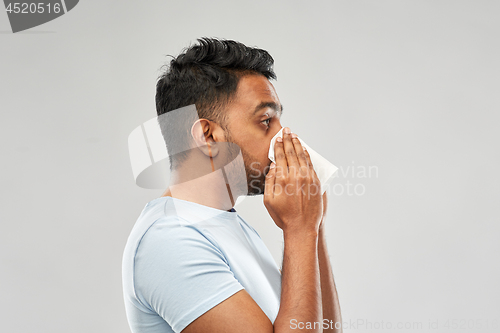 Image of indian man with paper napkin blowing nose