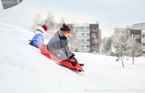 Image of kids sliding on sleds down snow hill in winter