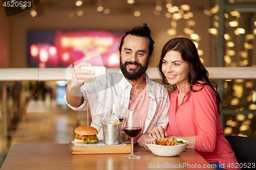 Image of couple taking selfie by smartphone at restaurant