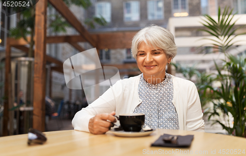 Image of senior woman drinking coffee at street cafe