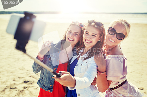 Image of group of smiling women taking selfie on beach