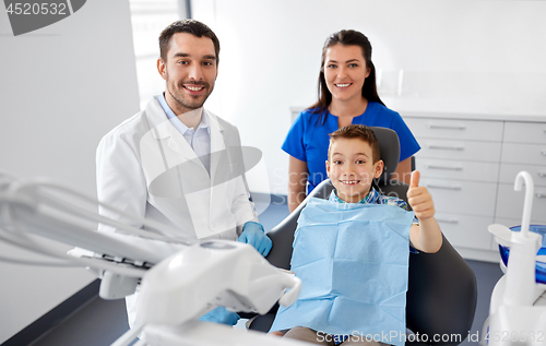 Image of dentist and boy showing thumbs up at dental clinic