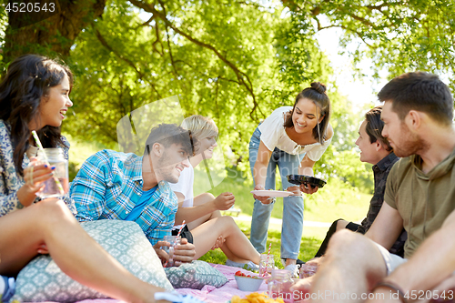 Image of friends with drinks and food at picnic in park