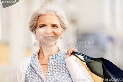 Image of senior woman with shopping bags in city