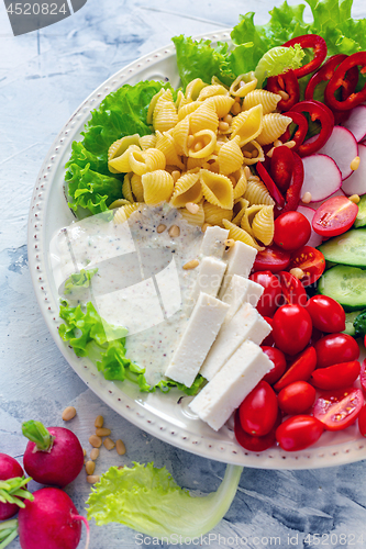 Image of Vegetable salad with pasta,artisanal cheese and pine nuts.