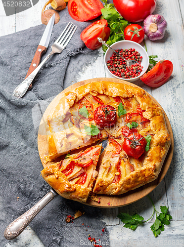 Image of Open pie with potatoes, bacon and tomatoes.