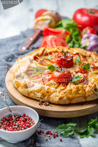 Image of Open pie with potatoes, bacon, onions and tomatoes.