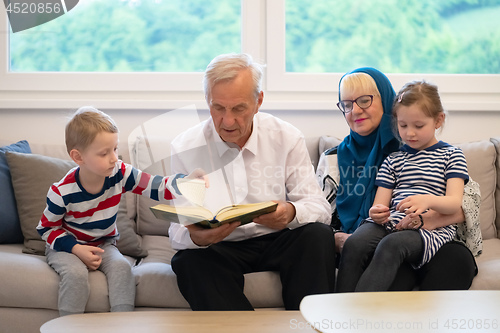 Image of modern muslim grandparents with grandchildren reading Quran