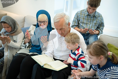 Image of modern muslim grandparents with grandchildren reading Quran