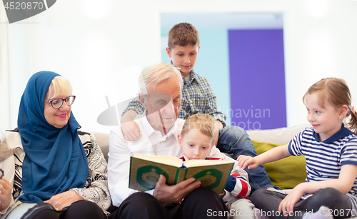 Image of modern muslim grandparents with grandchildren reading Quran