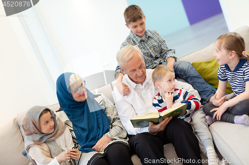 Image of modern muslim grandparents with grandchildren reading Quran