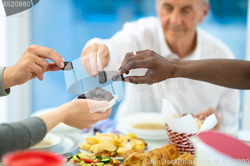 Image of modern multiethnic muslim family sharing a bowl of dates