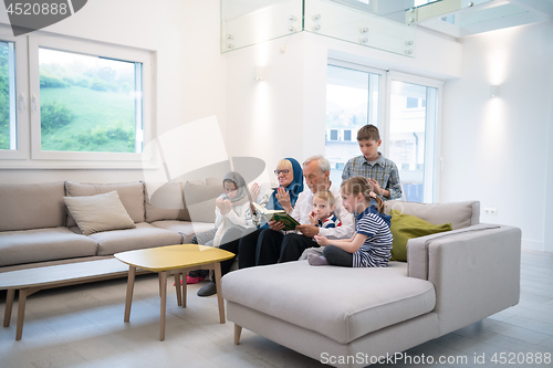 Image of modern muslim grandparents with grandchildren reading Quran