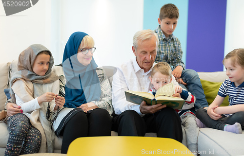 Image of modern muslim grandparents with grandchildren reading Quran