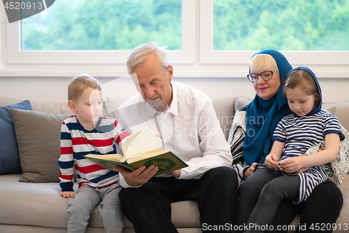 Image of modern muslim grandparents with grandchildren reading Quran