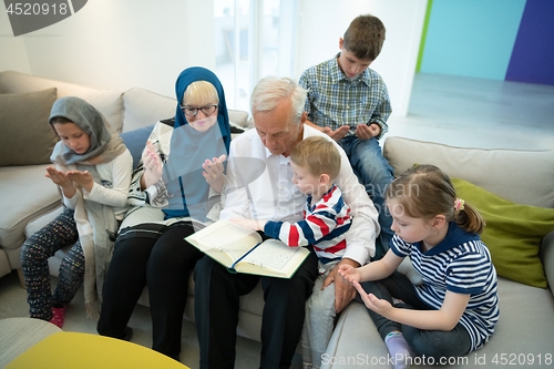 Image of modern muslim grandparents with grandchildren reading Quran