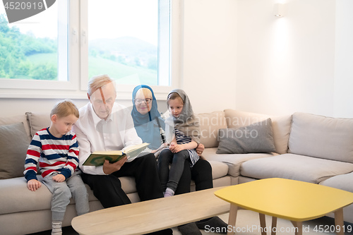 Image of modern muslim grandparents with grandchildren reading Quran