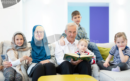 Image of modern muslim grandparents with grandchildren reading Quran