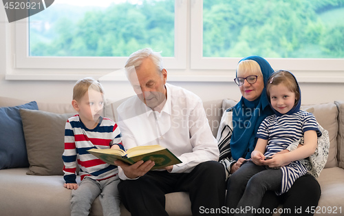 Image of modern muslim grandparents with grandchildren reading Quran