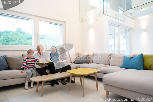 Image of modern muslim grandparents with grandchildren reading Quran