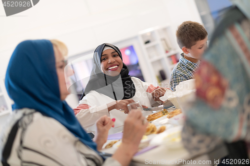 Image of black modern muslim woman enjoying iftar dinner with family