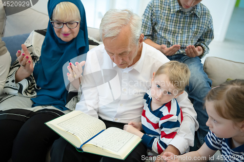 Image of modern muslim grandparents with grandchildren reading Quran