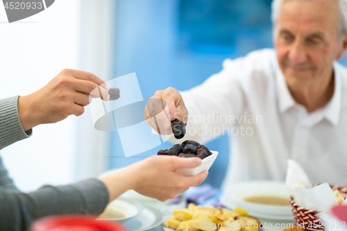 Image of modern multiethnic muslim family sharing a bowl of dates