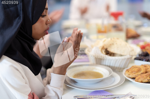 Image of modern black muslim woman praying before having iftar dinner