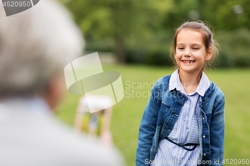 Image of little girl being photographed at summer park