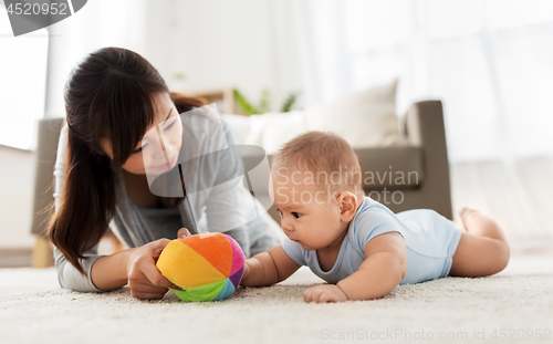 Image of mother and baby son playing with ball at home