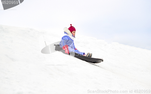 Image of happy little girl sliding down on sled in winter