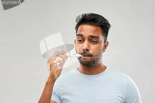 Image of man measuring oral temperature by thermometer