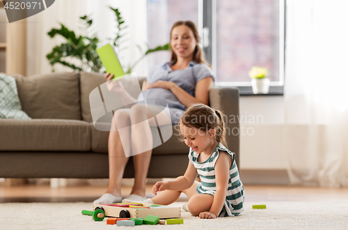 Image of happy baby girl playing with toy blocks at home