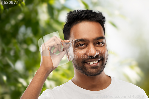 Image of indian man with tweezers tweezing eyebrow hair