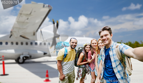 Image of friends taking selfie over plane on airfield