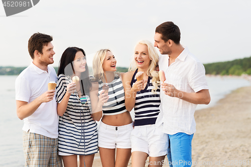 Image of happy friends eating ice cream on beach