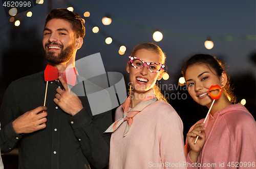 Image of happy friends with party props at rooftop